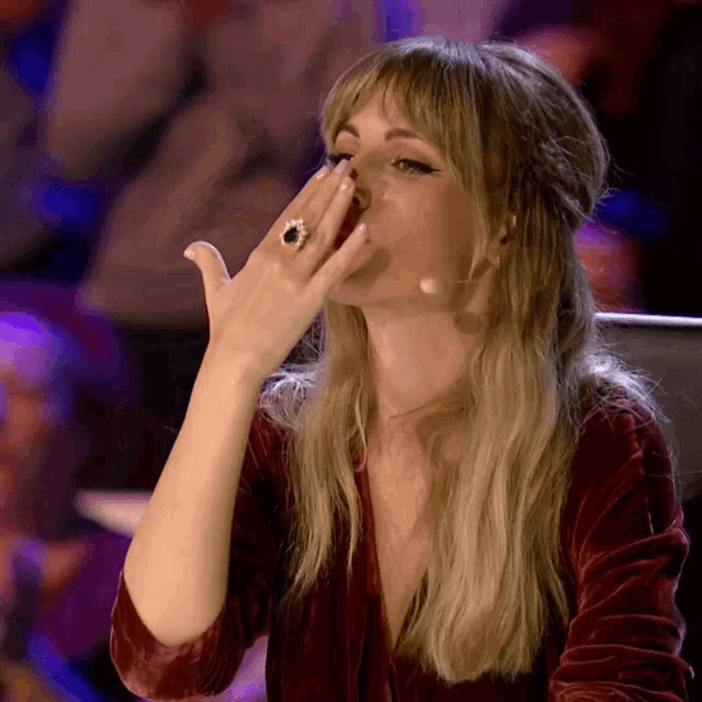 a woman with a ring on her finger covering her mouth with her hand