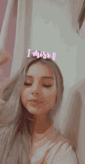 a woman is taking a picture of herself with the words i miss u on her forehead .