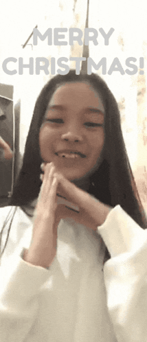 a girl says merry christmas with her hands on her chin