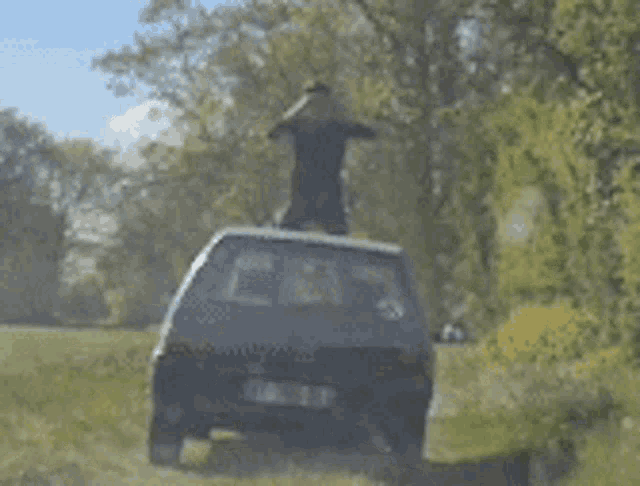 a man is standing on top of a car on a dirt road .