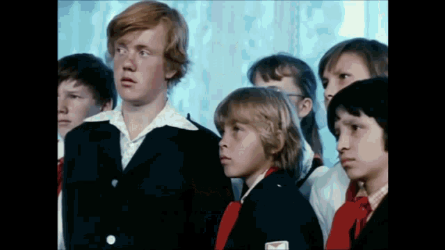 a group of children are standing in a room and one of them has a red bow tie
