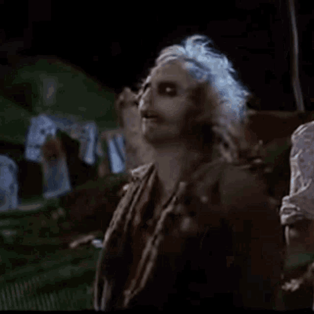 a man with white hair is standing in a dark room with a woman .
