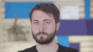 a man with a beard is looking at the camera with a blurred background .
