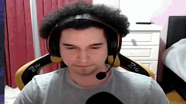 a man wearing headphones and a microphone is sitting in a chair with the word zig on it