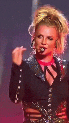 a woman in a black jacket with buttons on it is holding a pink object in her mouth