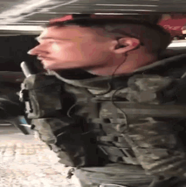 a man in a military uniform is wearing ear buds and a gun .