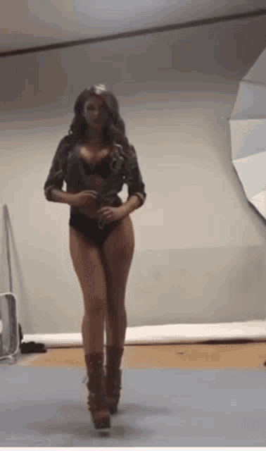a woman in lingerie is walking in a room with a umbrella in the background .