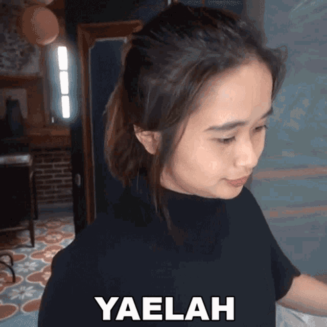 a woman in a black shirt with the word yaelah written on her chest