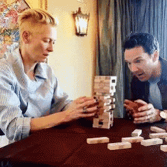 two people are playing jenga at a table