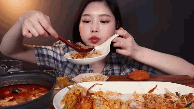 a woman in a plaid shirt is eating food with a ladle