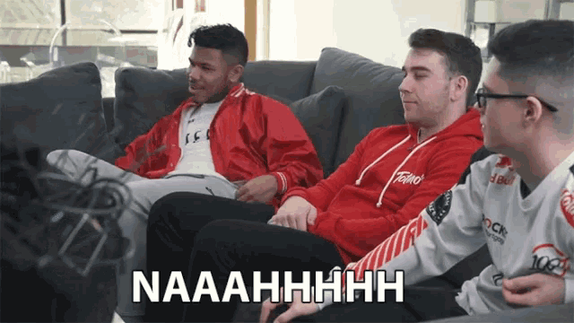 three men are sitting on a couch and one of them is wearing a red hoodie that says falcon