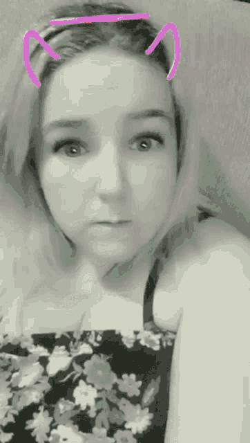 a woman wearing a floral dress and cat ears is making a funny face .