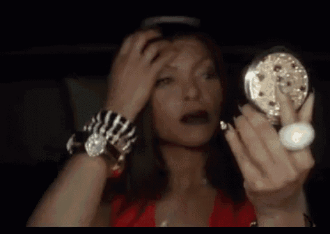 a woman is applying makeup to her face in front of a small mirror .