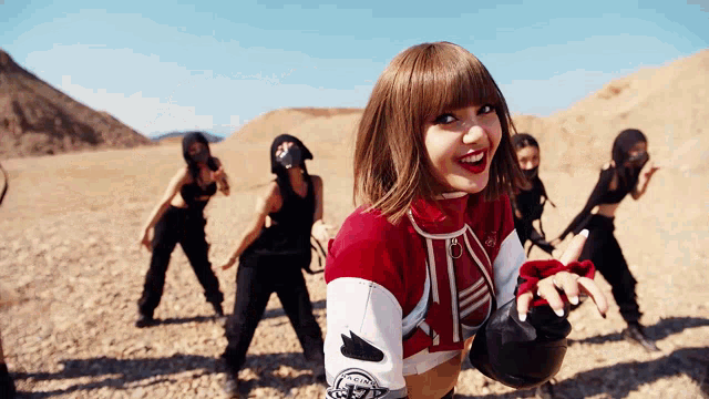 a group of women are dancing in the desert and one of them is wearing a red and white sweater with the letter a on it