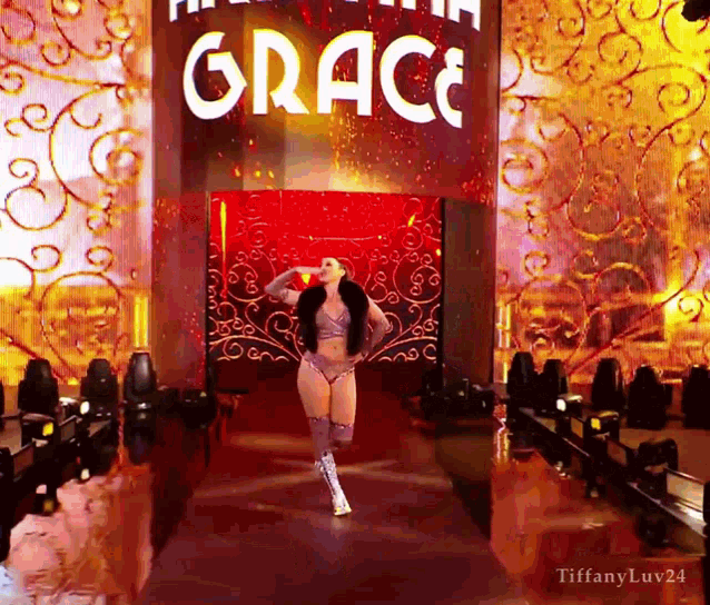 a woman is walking down a runway with a sign that says grace