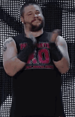 a man with a beard is wearing a black tank top with the number 10 on it and gloves .