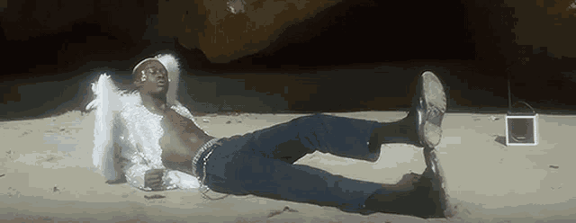 a man dressed as an angel is laying on the beach with his feet in the air .