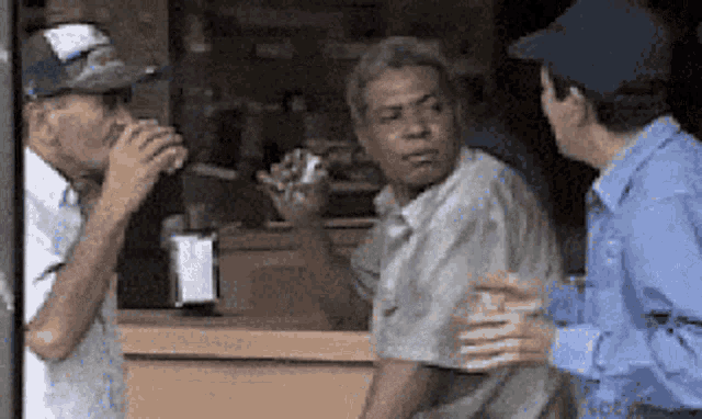 a man in a blue shirt is talking to a man in a hat