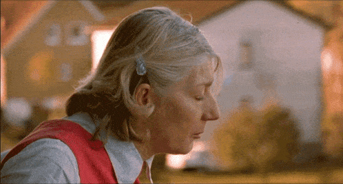 a close up of a woman 's face with a house behind her
