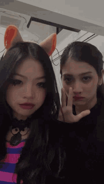 two girls are posing for a picture with one wearing a cat ear headband