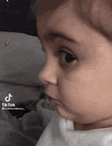 a baby is making a funny face while looking at something .