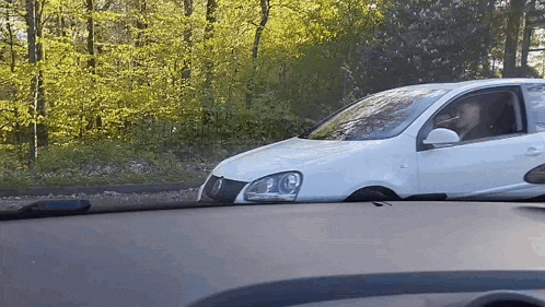 a man is driving a white car in the woods