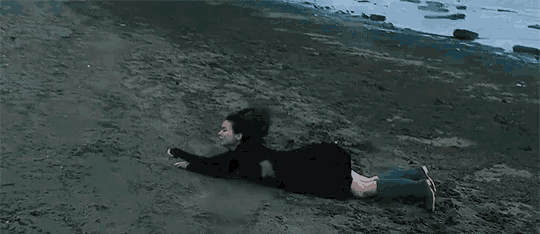a woman is laying on her stomach on a beach .