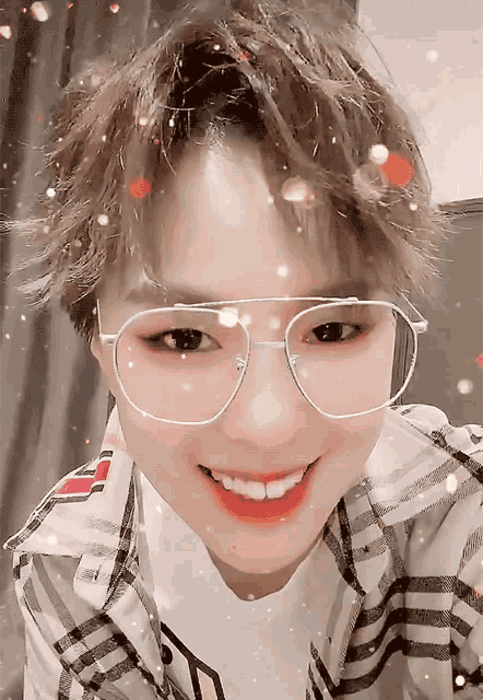 a woman wearing glasses and a plaid shirt smiles