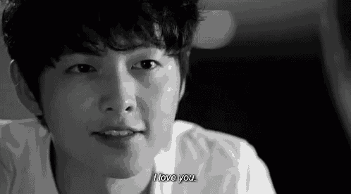 a black and white photo of a young man laying down and saying `` i love you '' .