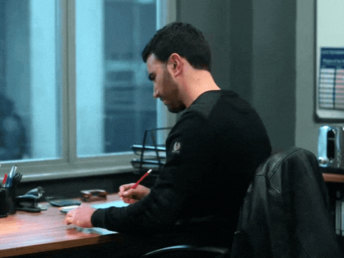 a man is sitting at a desk with a jacket that says belstaff on it