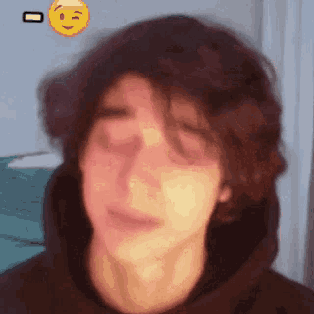 a close up of a young man 's face with a smiley face behind him .