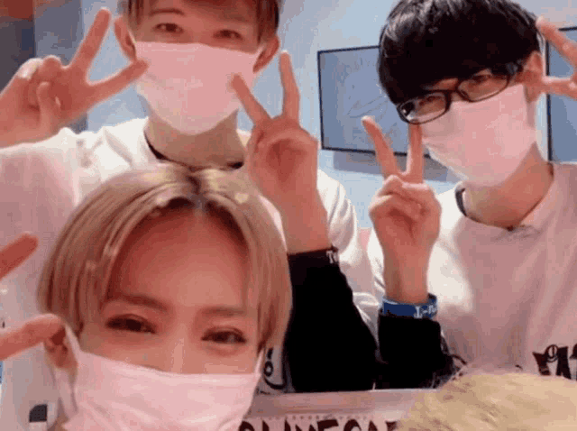 a group of people wearing face masks are giving a peace sign