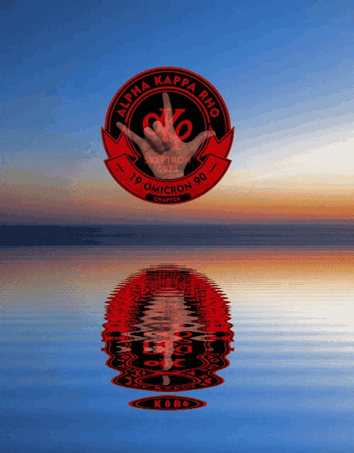 a red and black logo for alpha kappa rho is reflected in a body of water