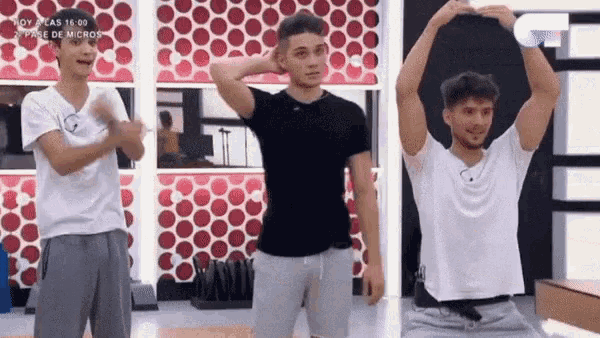 three young men are dancing in front of a wall with polka dots on it .