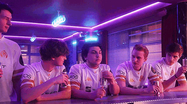 a group of young men are sitting at a bar drinking
