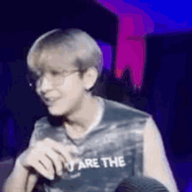 a man wearing glasses and a tank top that says `` i 'm the '' is talking into a microphone .