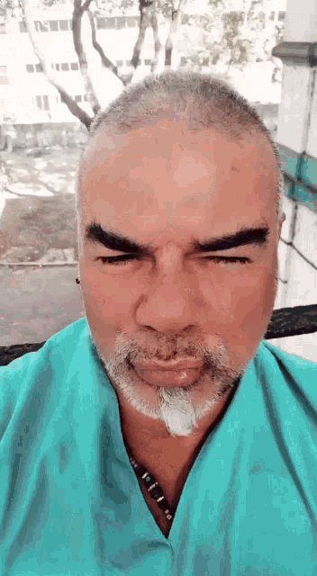 a man with a beard is wearing a green shirt and making a funny face