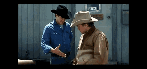 two cowboys shake hands in front of an office