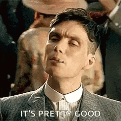 a man in a suit is smoking a cigarette and saying it 's pretty good .