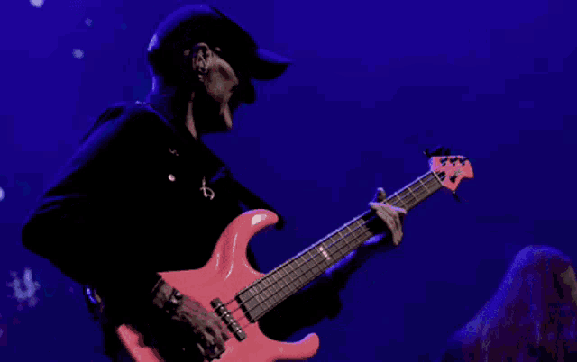 a man playing a pink guitar with the letter e on the neck