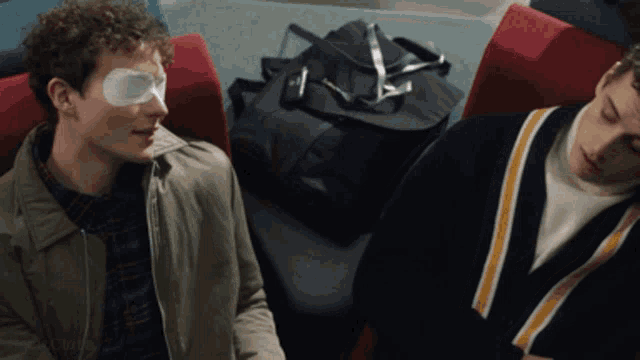 a man with an eye patch sits next to another man