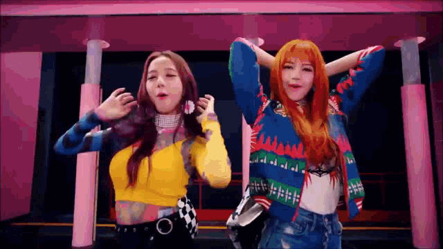 two women are standing next to each other in a pink room and dancing .