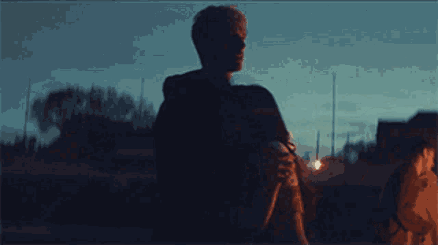 a man in a hoodie is standing in the dark holding a frisbee .