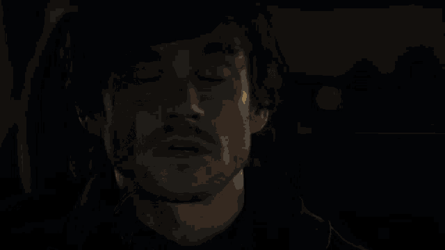 a person covering their face with their hands in the dark