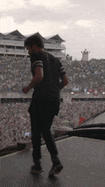 a man in a black shirt is walking on a stage in front of a crowd