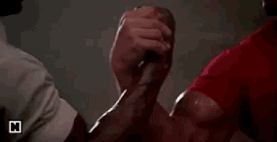 a man in a white shirt is hugging another man in a room .