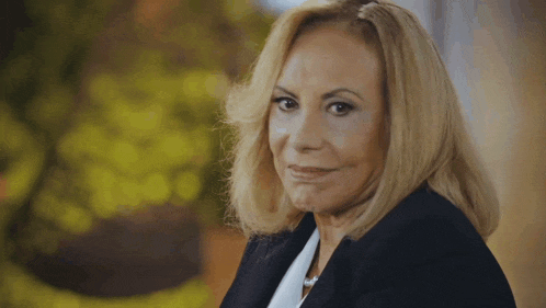 a woman with blonde hair is wearing a black jacket and a white shirt