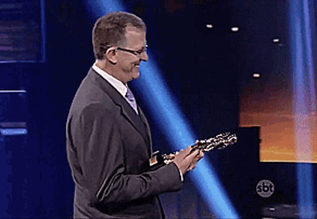 a man in a suit is holding a trophy in front of a sbt sign