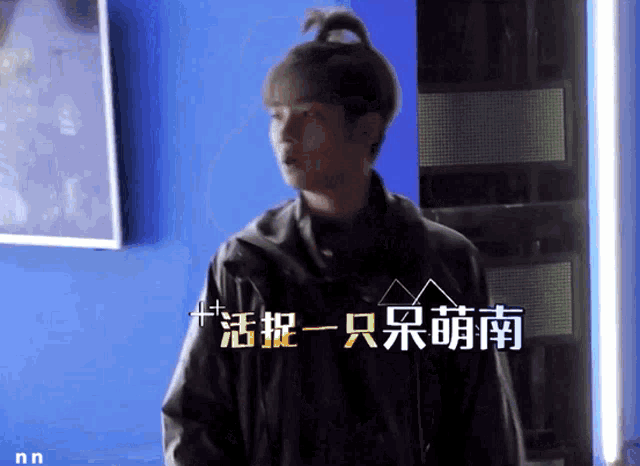 a man with a bun on his head is standing in front of a blue wall