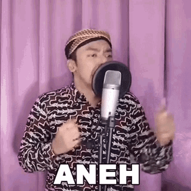 a man is singing into a microphone while wearing a hat and a shirt .